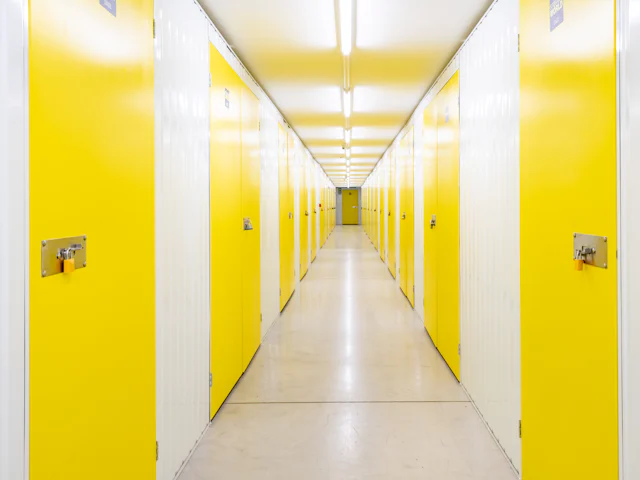 A bright hallway of yellow self-storage unit doors